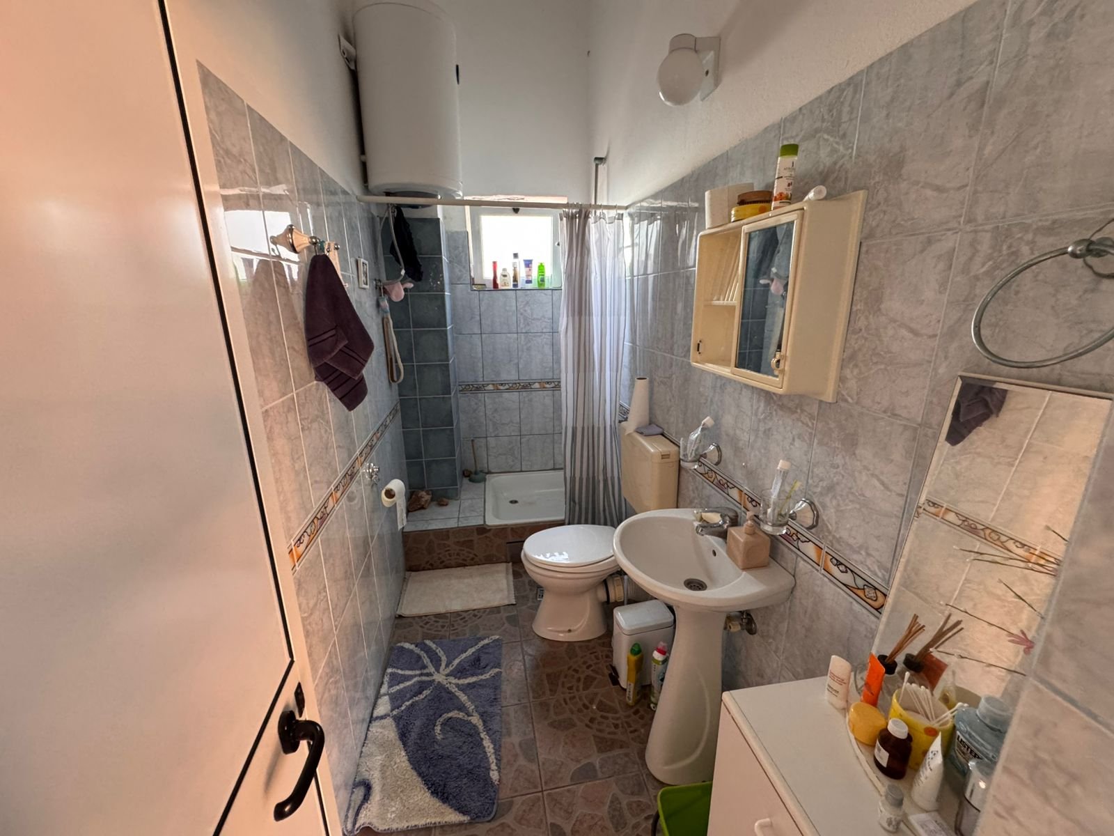 Modern tiled bathroom in Ulcinj, with shower, storage, and fixtures&mdash;ideal Montenegro real estate investment at immorenta.me by ekosphere doo.