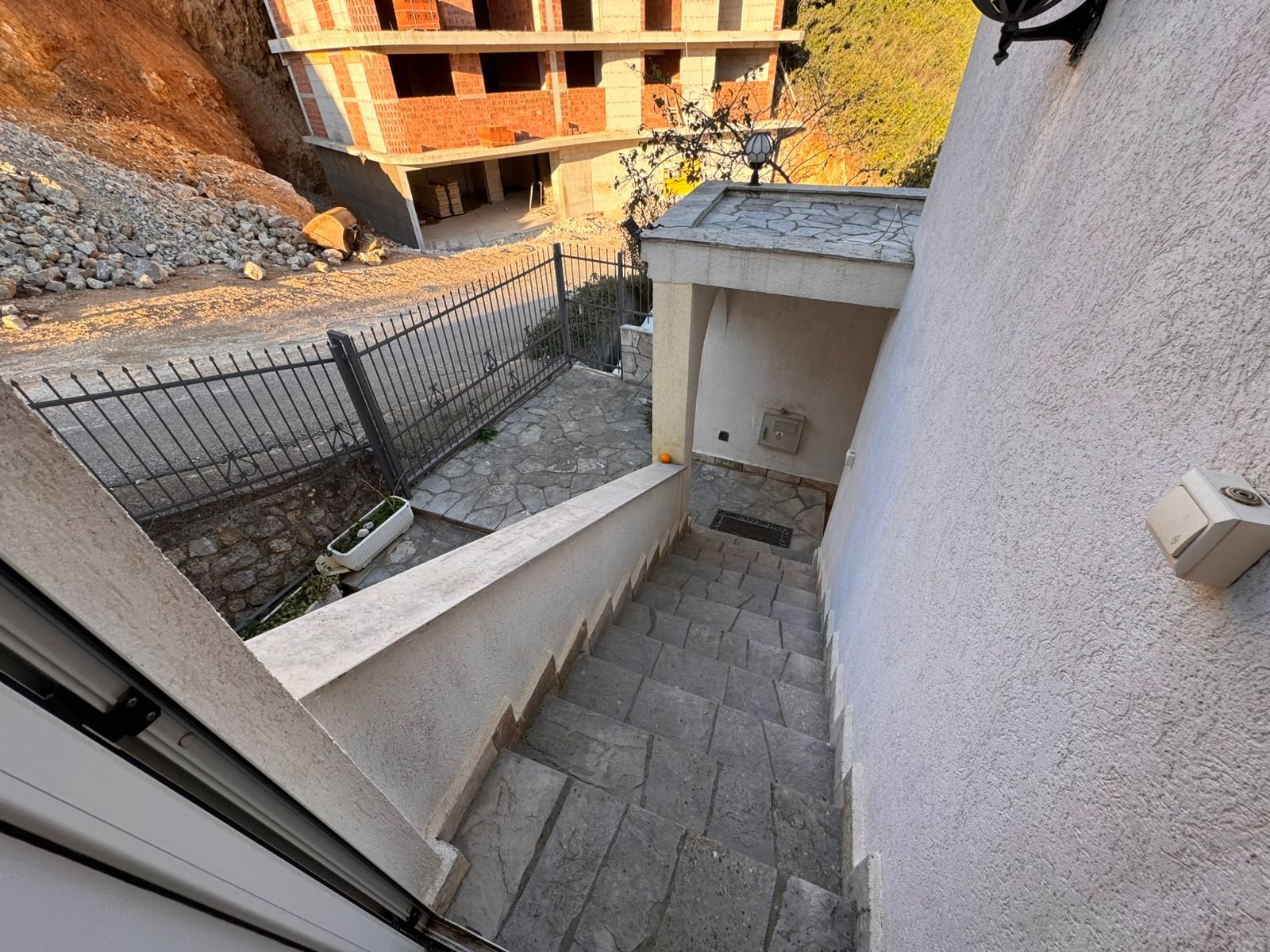 Elegant stone staircase descends to gated entry, overlooking new development potential in Ulcinj. Exclusive on immorenta.me by ekosphere doo.