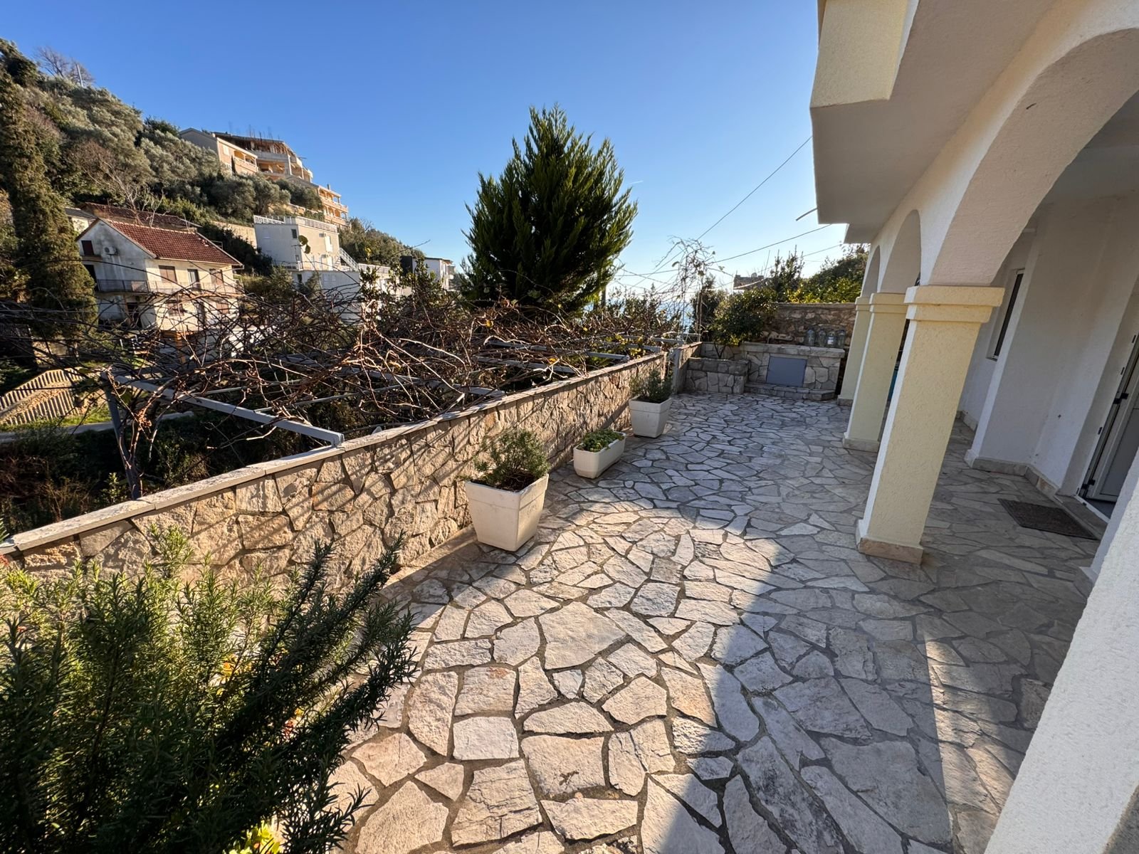 Elegant stone terrace with potted plants, arches, and scenic Ulcinj views. Prime investment via immorenta.me by ekosphere doo.