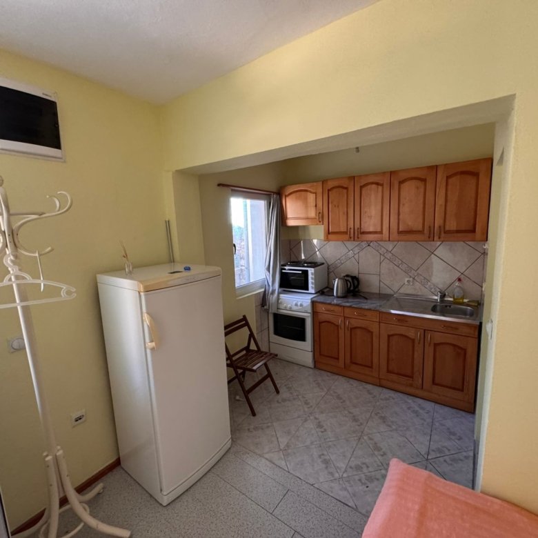Bright kitchen in Ulcinj with wooden cabinetry, appliances, and sunny yellow walls&mdash;prime Montenegro investment via ekosphere doo.