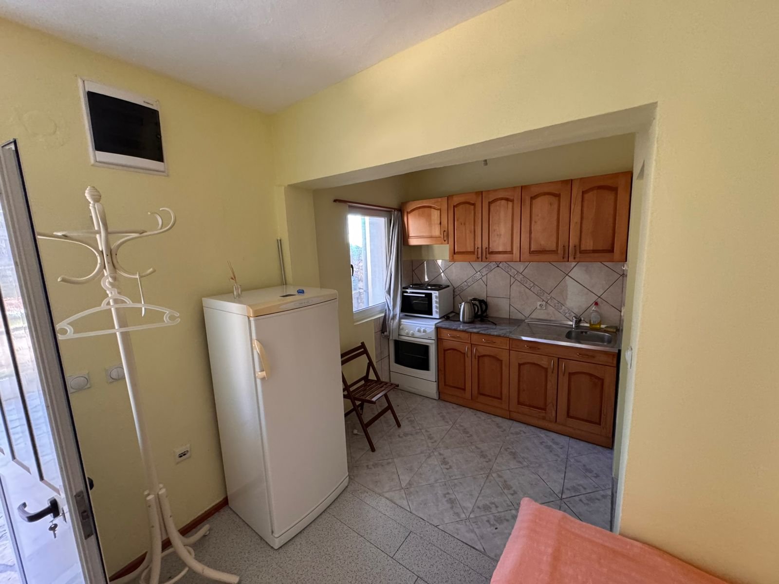 Bright kitchen in Ulcinj with wooden cabinetry, appliances, and sunny yellow walls&mdash;prime Montenegro investment via ekosphere doo.
