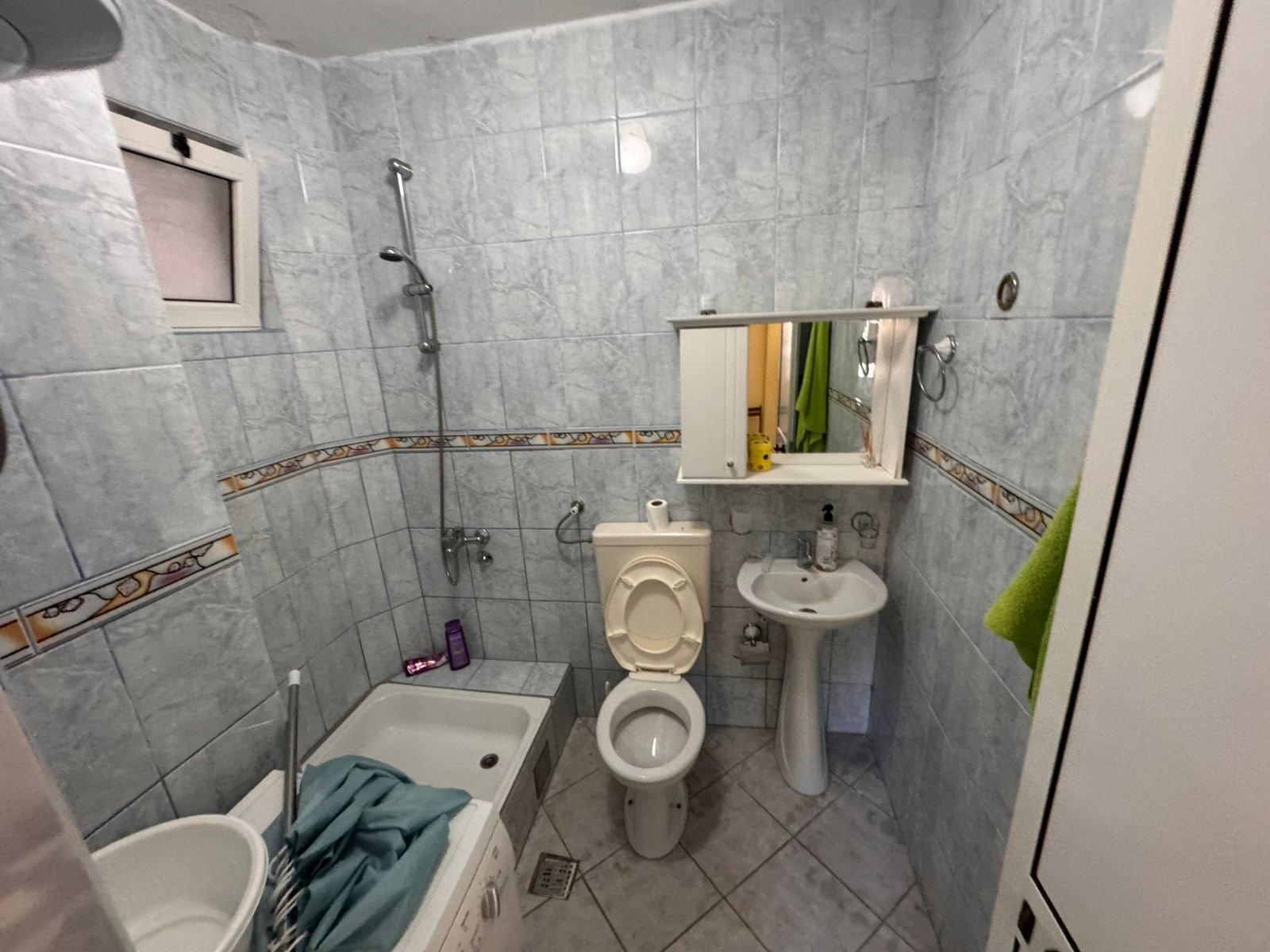Modern tiled bathroom in Ulcinj features bathtub, handheld shower, wall-mounted sink, and storage&mdash;ideal Montenegro real estate investment.