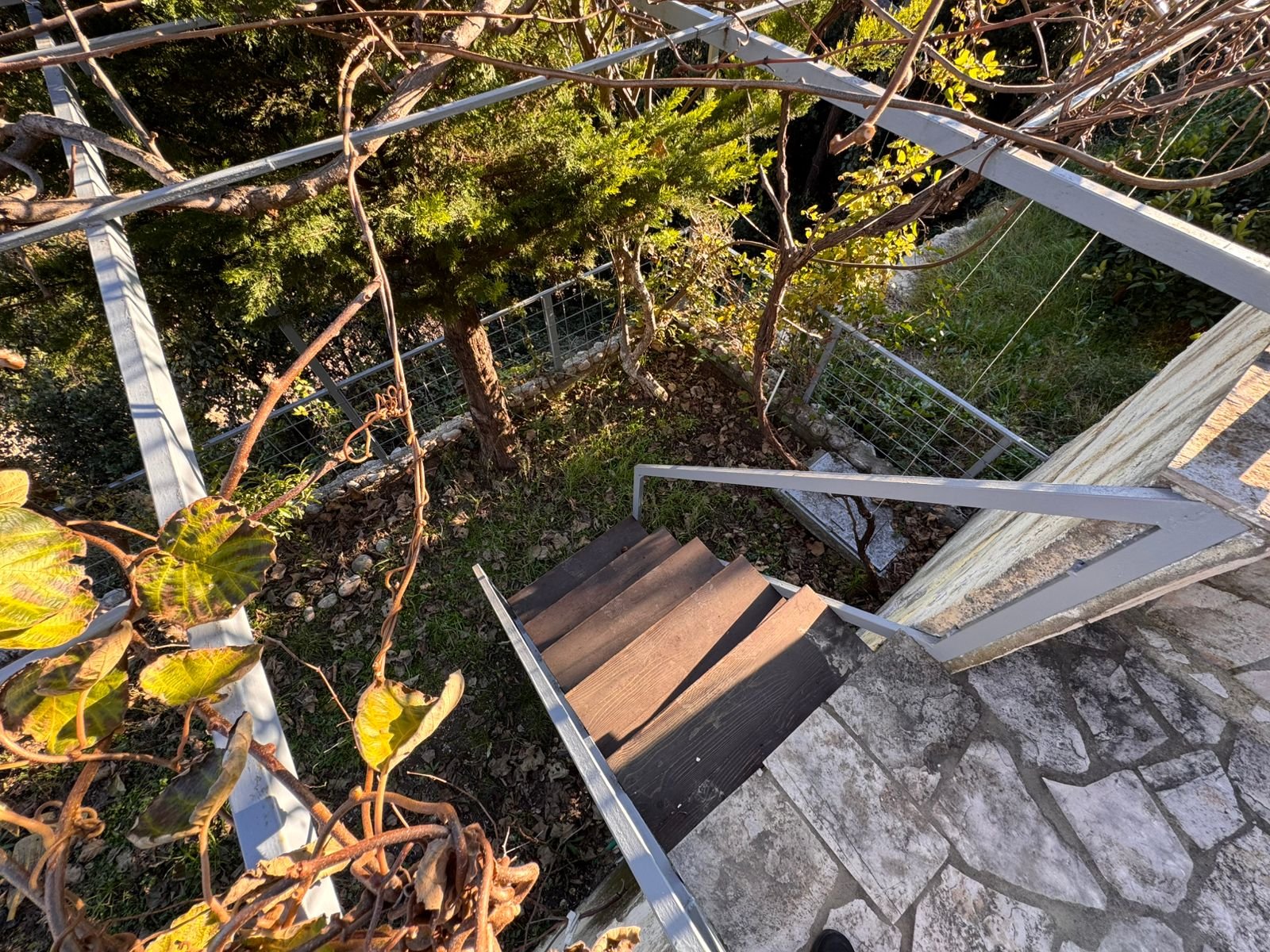 Elegant outdoor wooden stairs with sleek metal railings, lush greenery, and secure fencing&mdash;prime Ulcinj investment via immorenta.me by ekosphere doo.