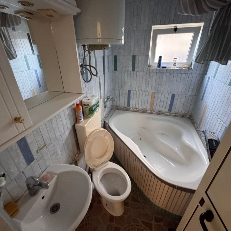 Modern Ulcinj bathroom with corner bathtub, blue-white tiles, window, quality fittings&mdash;an ideal real estate investment. Montenegro-listings.me by ekosphere doo.