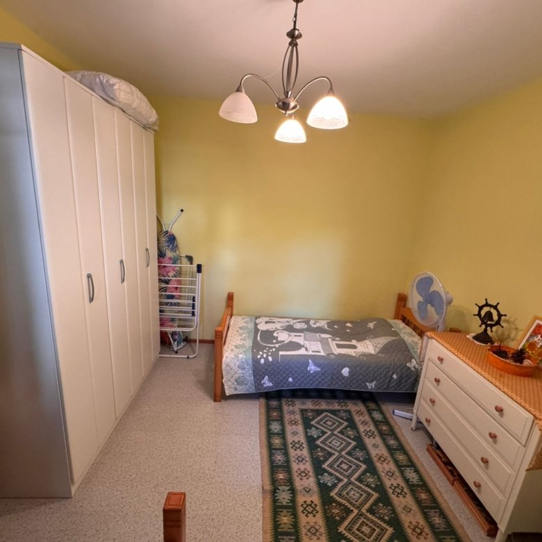 Charming Ulcinj bedroom for sale: yellow walls, modern gray bedding, ample storage, ideal Montenegro investment. Eksosphere DOO project.