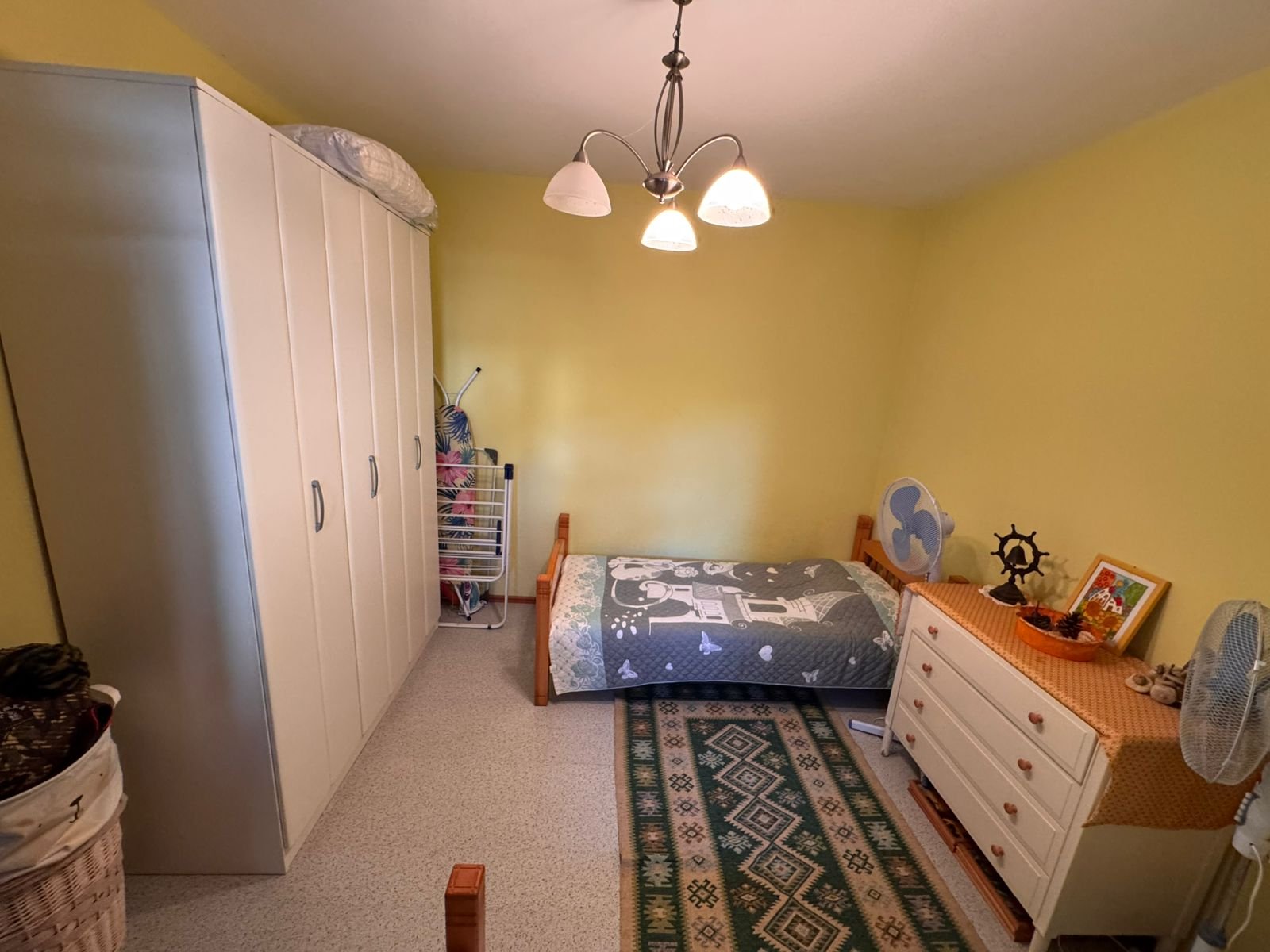 Charming Ulcinj bedroom for sale: yellow walls, modern gray bedding, ample storage, ideal Montenegro investment. Eksosphere DOO project.