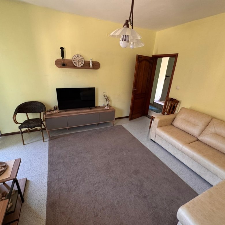 Bright Ulcinj living room with yellow walls, stylish beige sofa, modern TV, and quality finishes. Invest via immorenta.me by ekosphere doo.