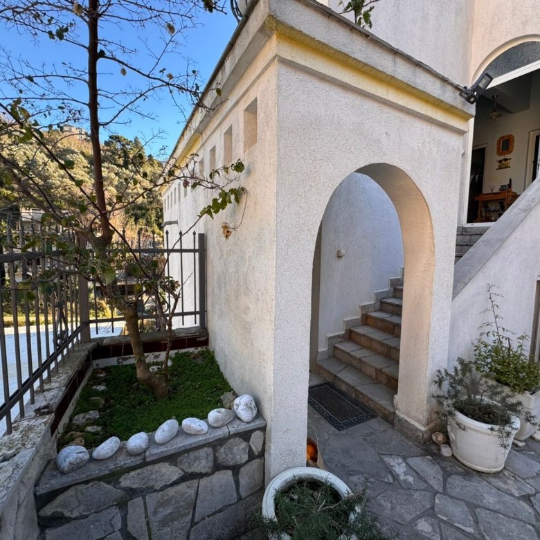 Prime Ulcinj property: Elegant white residence with arched entry, stone steps, garden, and secure fence. Invest via immorenta.me by ekosphere doo.
