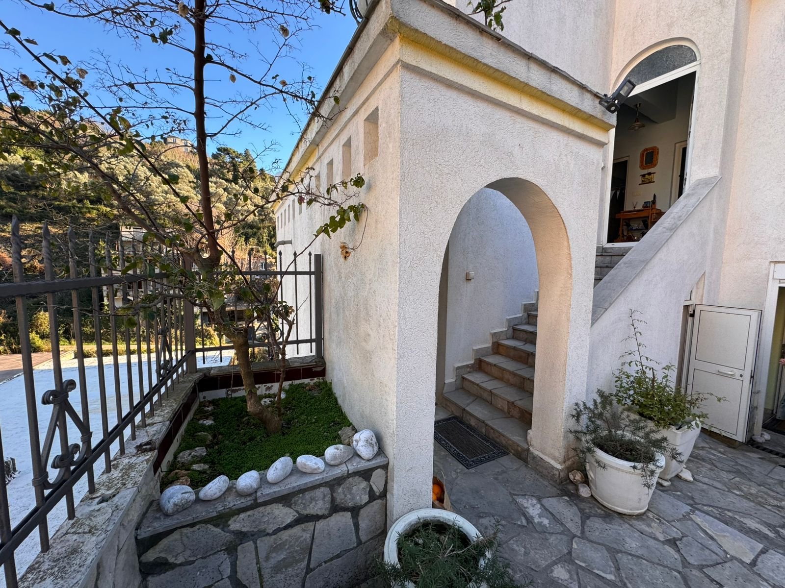 Prime Ulcinj property: Elegant white residence with arched entry, stone steps, garden, and secure fence. Invest via immorenta.me by ekosphere doo.