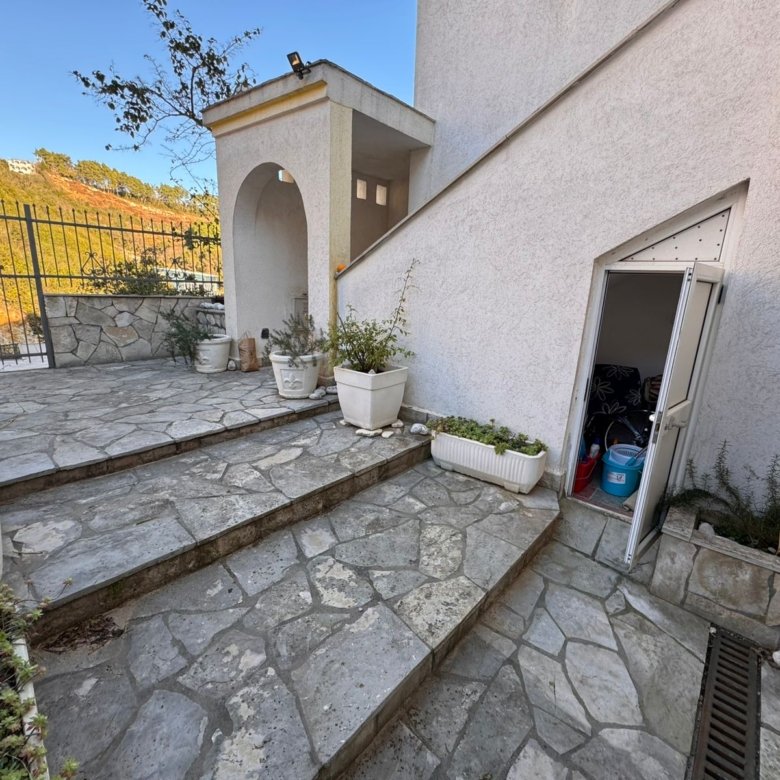 Elegant stone-paved terrace with landscaped planters, steps to a white Ulcinj home. Exclusive Montenegro investment by ekosphere doo.