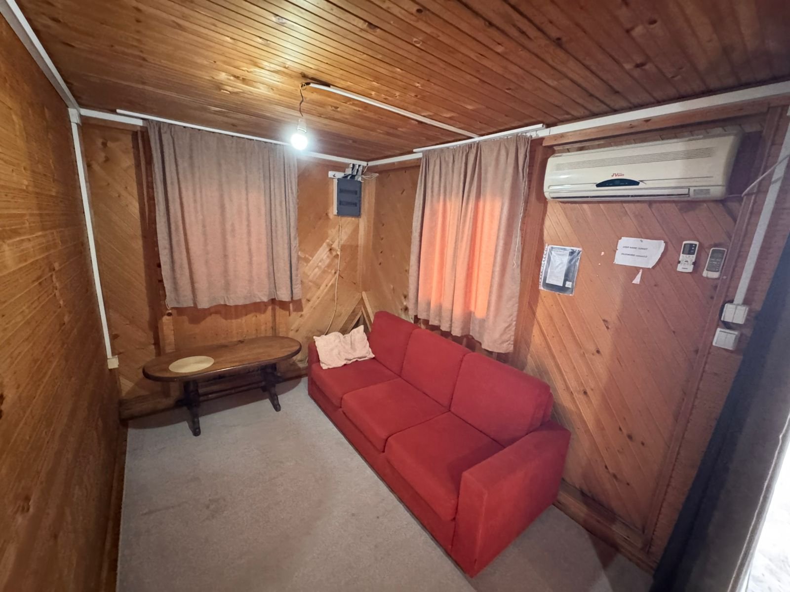 Charming Ulcinj studio: wood accents, modern AC, cozy red sofa, bright windows. Prime Montenegro investment&mdash;exclusive on immorenta.me by ekosphere doo.