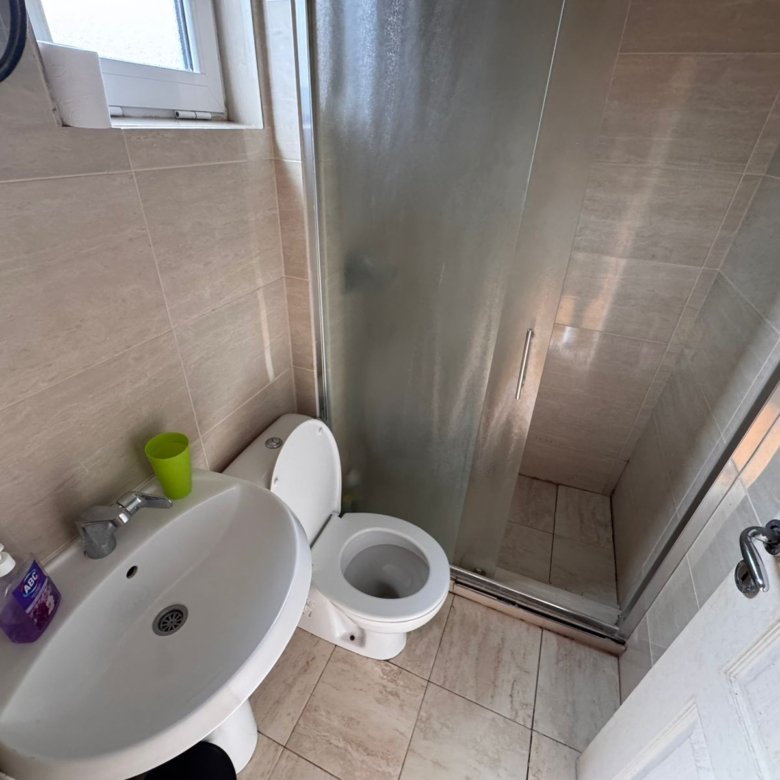 Modern Ulcinj bathroom with beige tiles, glass shower, window, and stylish fixtures&mdash;prime property via immorenta.me by ekosphere doo.