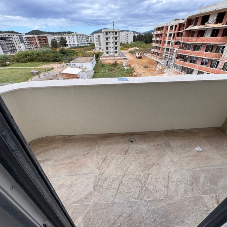 Modern tiled balcony with elegant curved railing, overlooking new development in Ulcinj. Prime Montenegro investment by ekosphere doo.