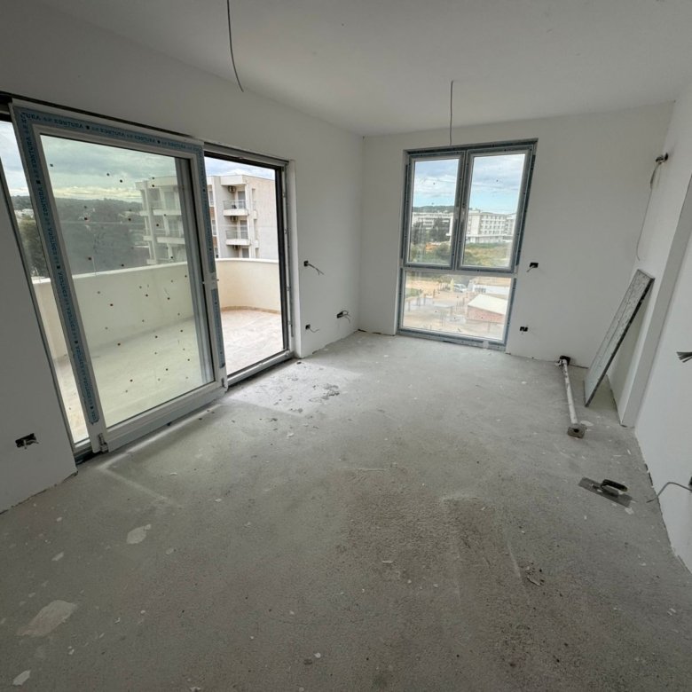 Spacious unfinished room in Ulcinj with large windows, balcony access, and city views&mdash;prime Montenegro investment via ekosphere doo.