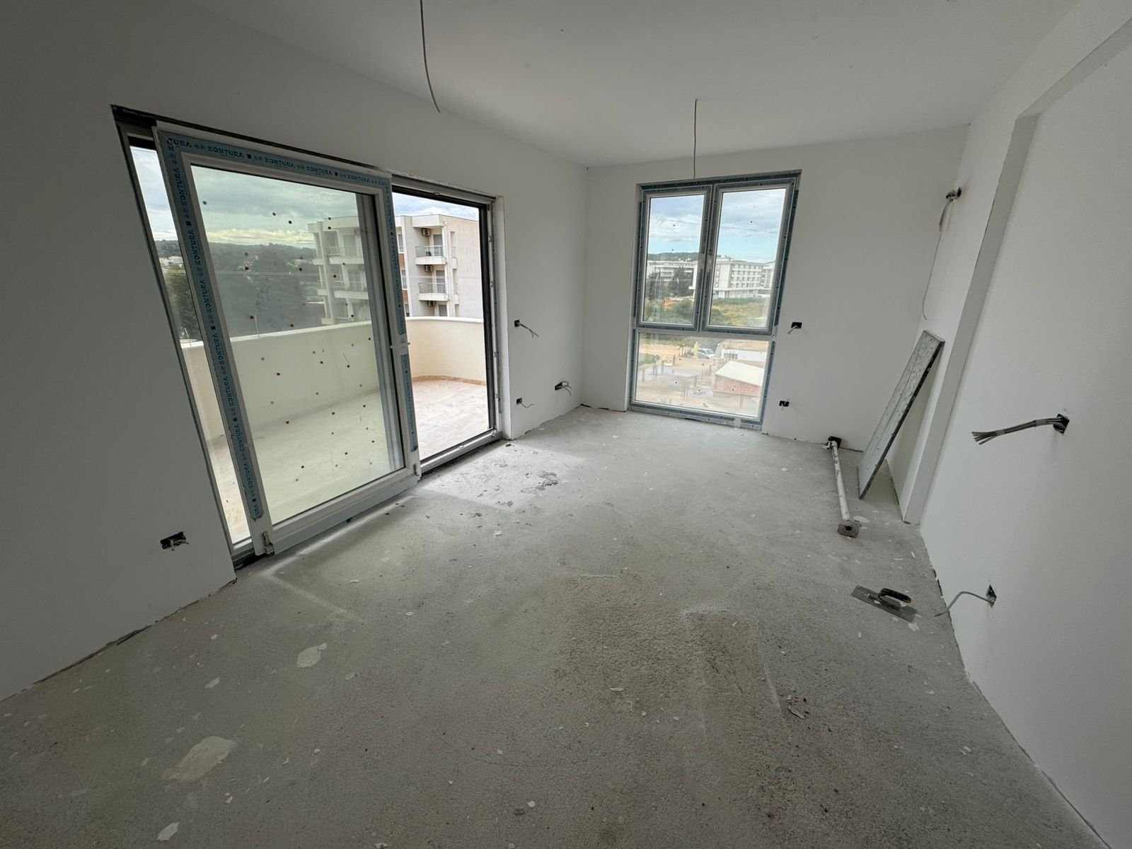 Spacious unfinished room in Ulcinj with large windows, balcony access, and city views&mdash;prime Montenegro investment via ekosphere doo.