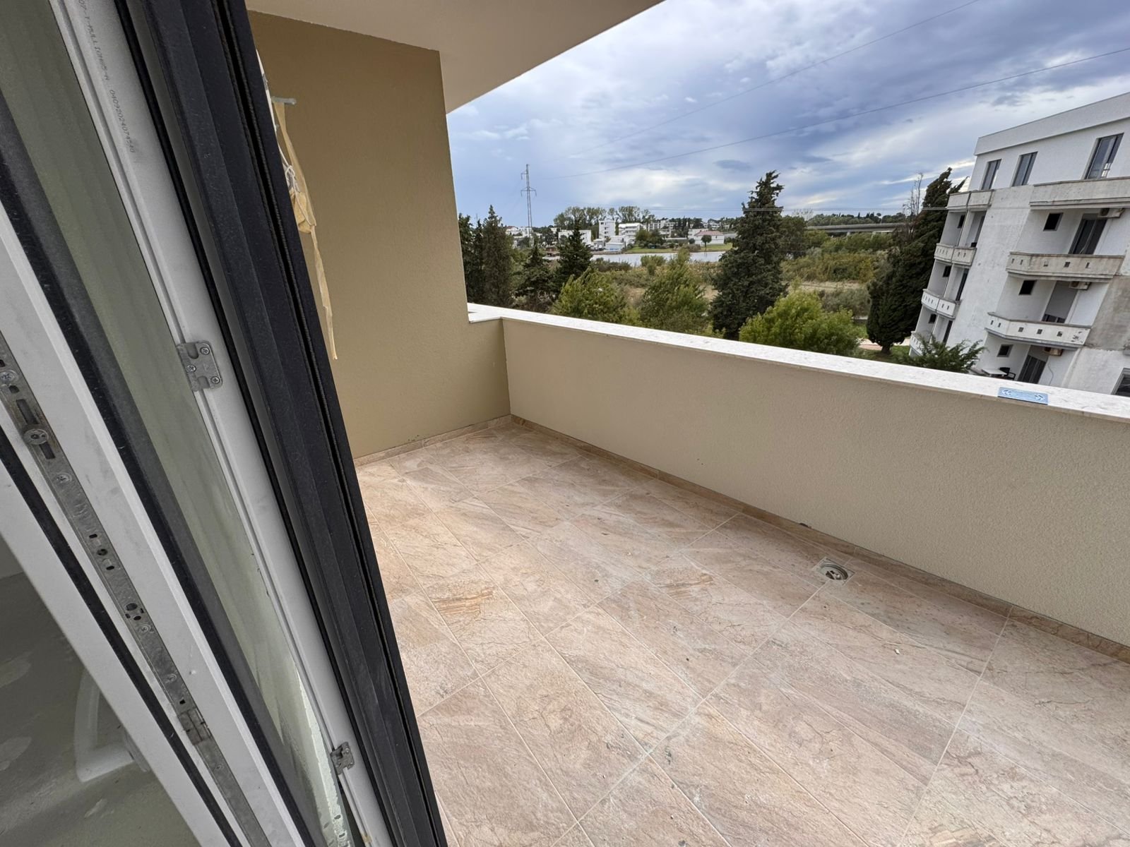 Spacious tiled balcony with beige walls, open views to greenery and nearby apartments&mdash;prime Ulcinj real estate by immorenta.me.