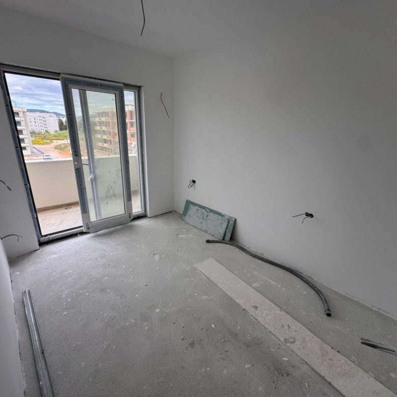 Spacious unfinished apartment in Ulcinj with white walls, large glass balcony door, and investment potential&mdash;exclusive to immorenta.me.