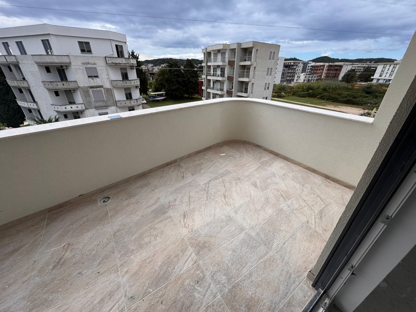 Spacious tiled balcony in Ulcinj with beige floors, cream walls, modern views&mdash;ideal Montenegro investment. View at immorenta.me by ekosphere doo.