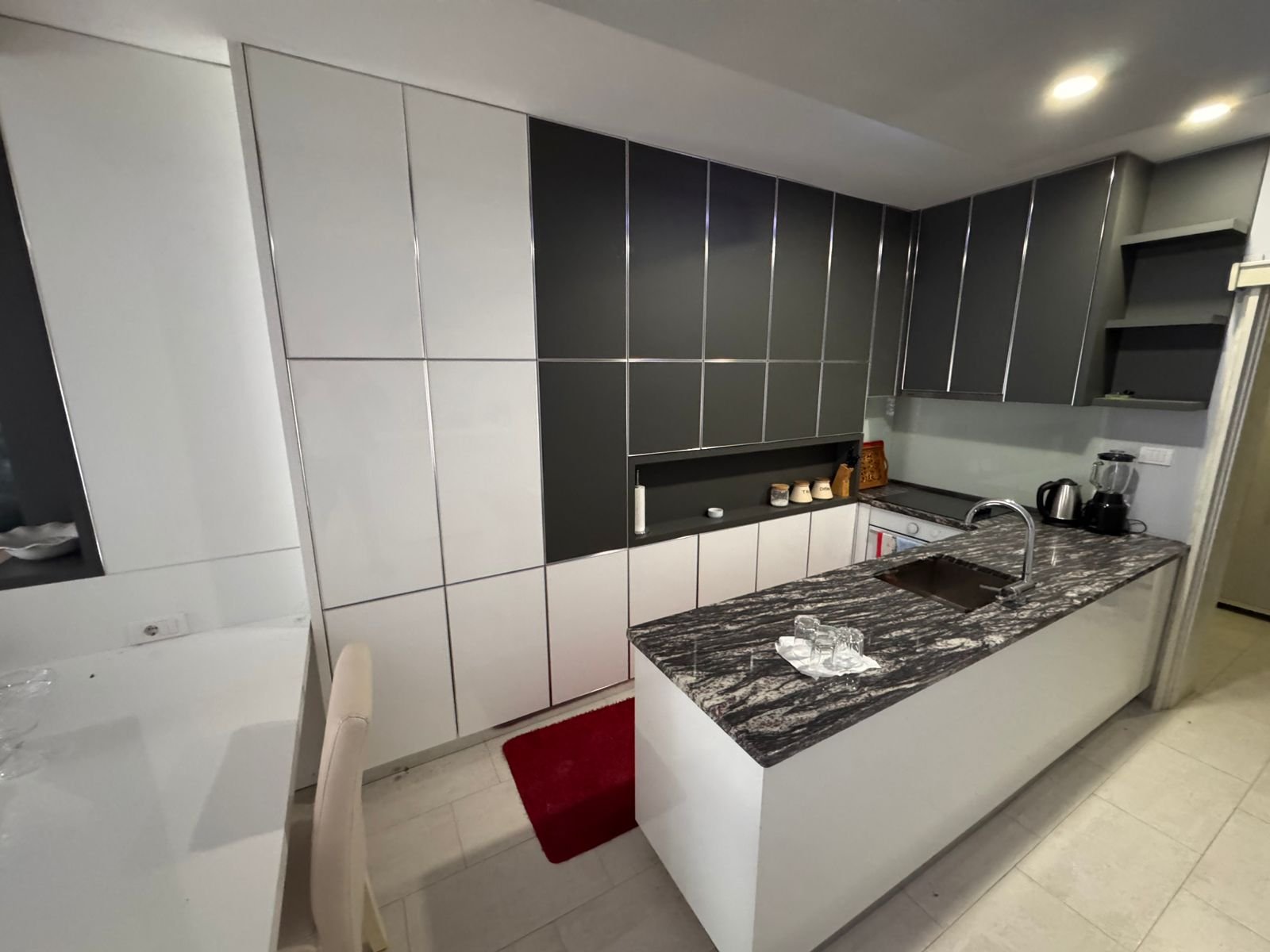 Stunning modern kitchen in Ulcinj, Montenegro&mdash;white & gray cabinetry, marbled island, premium appliances. Invest via immorenta.me.