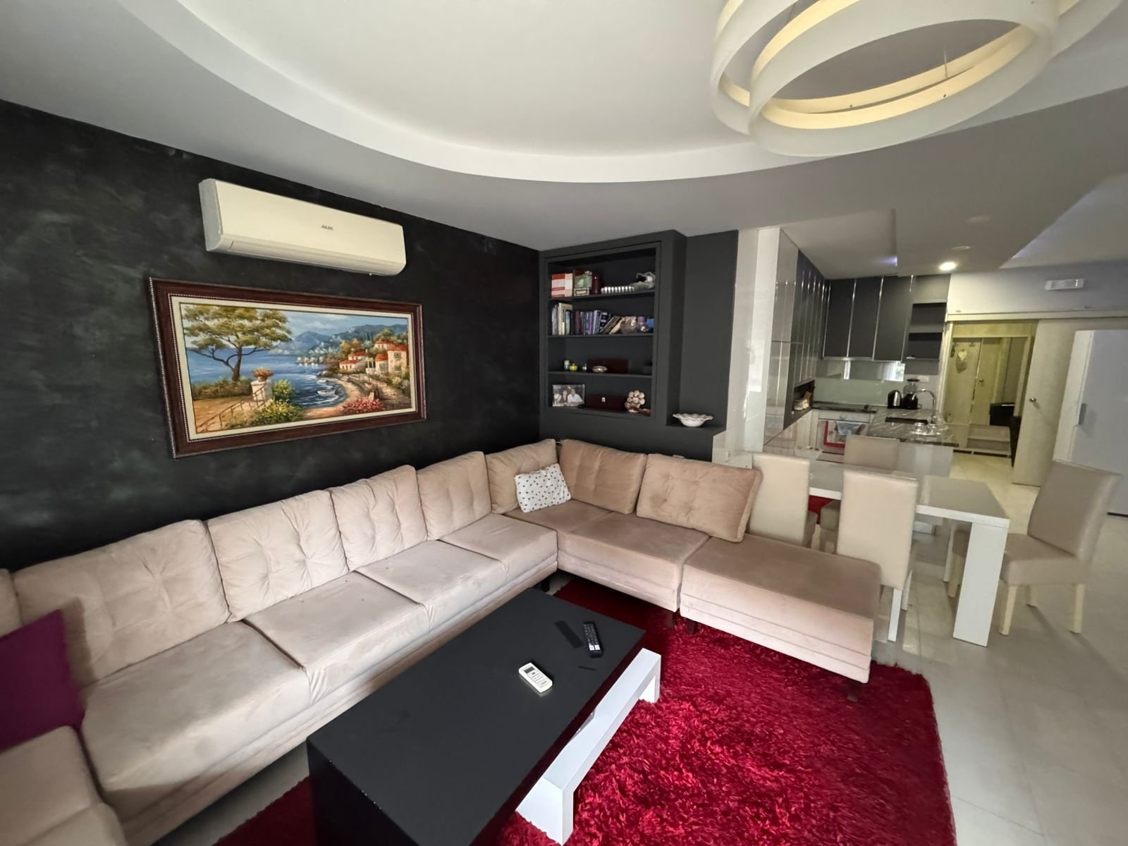 Stylish Ulcinj apartment: modern living room, beige L-sofa, red rug, open kitchen/dining. Prime Montenegro investment&mdash;ekosphere doo.