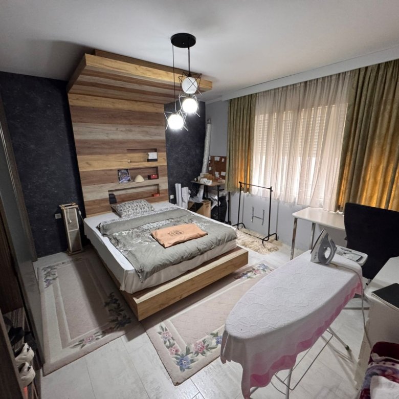 Stylish Ulcinj bedroom with wooden bed, modern lighting, desk, large green-curtained windows. Exclusive on immorenta.me by ekosphere doo.