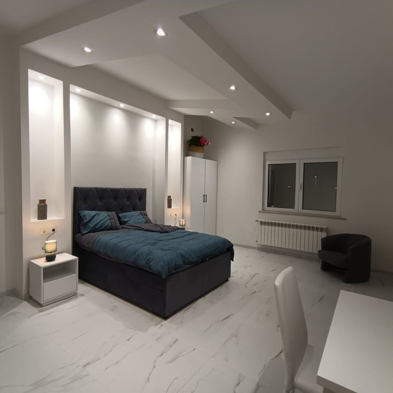 Modern Ulcinj bedroom with white interiors, stylish blue bed, office space, and premium features&mdash;exclusive at immorenta.me.