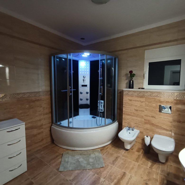 Elegant Ulcinj bathroom with tan tiles, blue-lit shower, premium fixtures&mdash;exclusive Montenegro investment via immorenta.me.