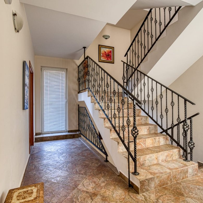 Elegant staircase with brown tiles, black railings, and stylish hallway&mdash;ideal Ulcinj investment! immorenta.me by ekosphere doo.