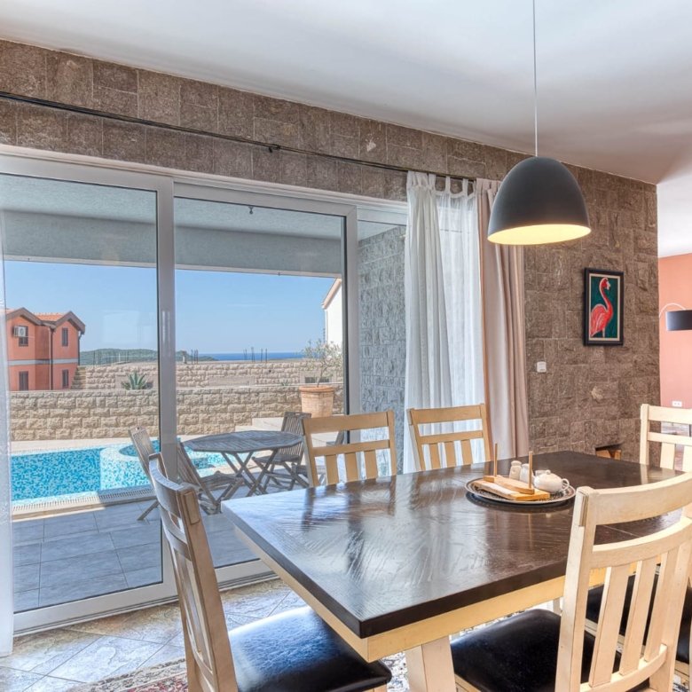Elegant dining area with stone walls, designer lighting, pool access, and stylish interiors&mdash;invest in Ulcinj Montenegro real estate today!.