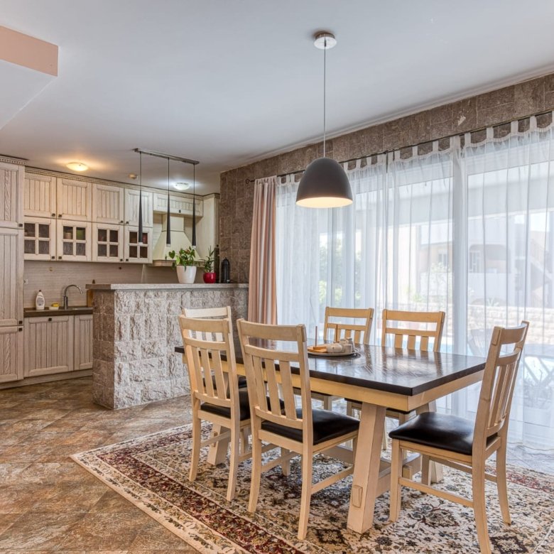Modern Ulcinj apartment: spacious dining with wooden table, stylish kitchen, sunlit windows&mdash;ideal Montenegro investment. Eksophere doo.
