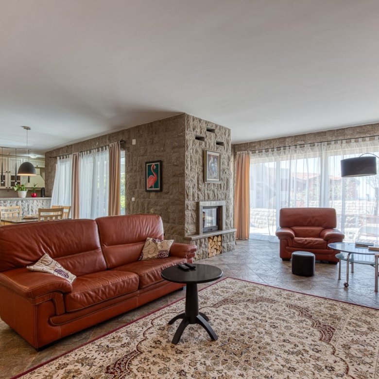 Elegant Ulcinj living room: brown leather sofas, stone feature wall, large windows. Ideal Montenegro investment&mdash;immorenta.me by ekosphere doo.