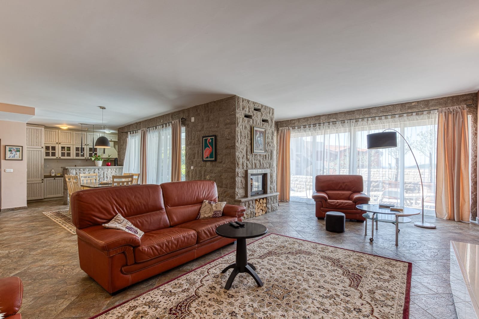 Elegant Ulcinj living room: brown leather sofas, stone feature wall, large windows. Ideal Montenegro investment&mdash;immorenta.me by ekosphere doo.