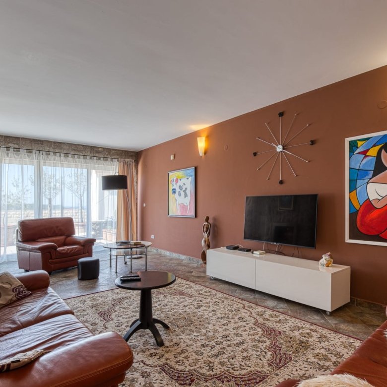 Elegant Ulcinj living room: brown leather sofas, modern art, large windows, ideal Montenegro real estate via immorenta.me by ekosphere doo.