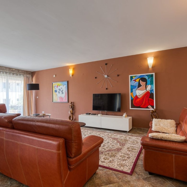 Stylish Ulcinj living room: brown leather sofas, large windows, premium details. Invest in Montenegro real estate at immorenta.me by ekosphere doo.