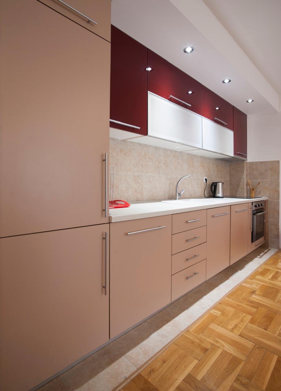 Stylish modern kitchen in Ulcinj, Montenegro: beige and maroon cabinets, parquet floors, tiled backsplash. Listed on immorenta.me by ekosphere doo&mdash;ideal property investment.