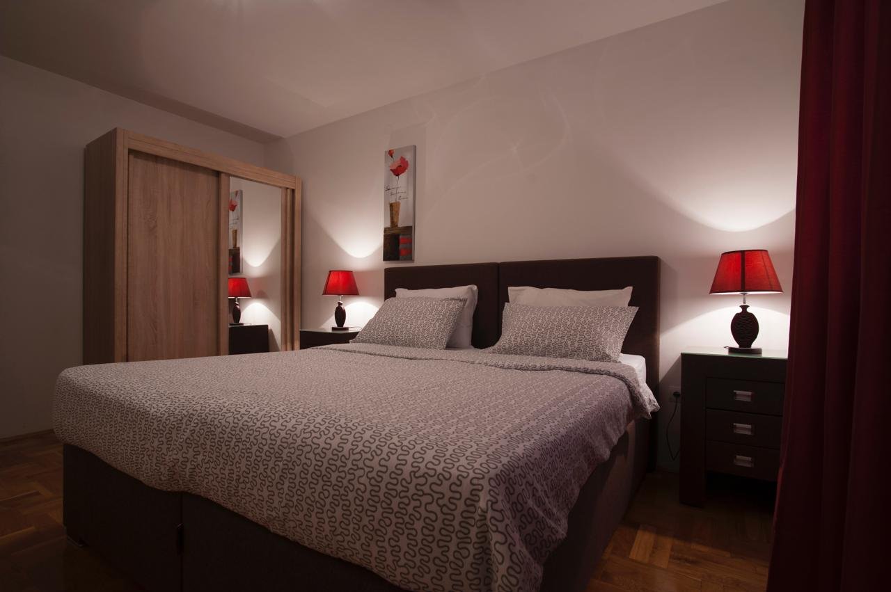 Stylish Ulcinj bedroom with a double bed, mirrored wardrobe, and chic red accents&mdash;exclusive listing on immorenta.me.