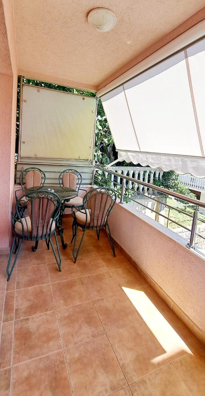 Stylish tiled balcony in Ulcinj with glass table, 4 cushioned chairs, greenery views. Invest via immorenta.me by ekosphere doo.