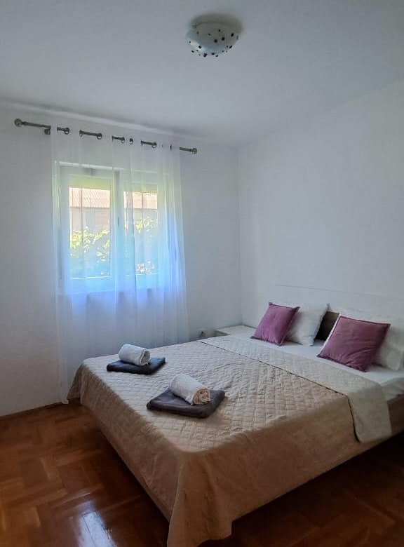 Elegant Ulcinj bedroom with parquet floors, king bed, chic mauve accents, and natural light&mdash;exclusive on immorenta.me by ekosphere doo.