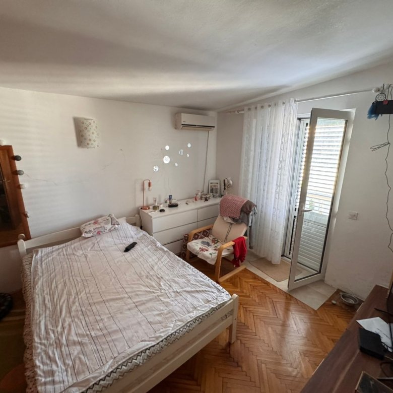 Bright Ulcinj bedroom with balcony access, stylish furnishings, AC, and TV&mdash;ideal Montenegro real estate investment by ekosphere doo.