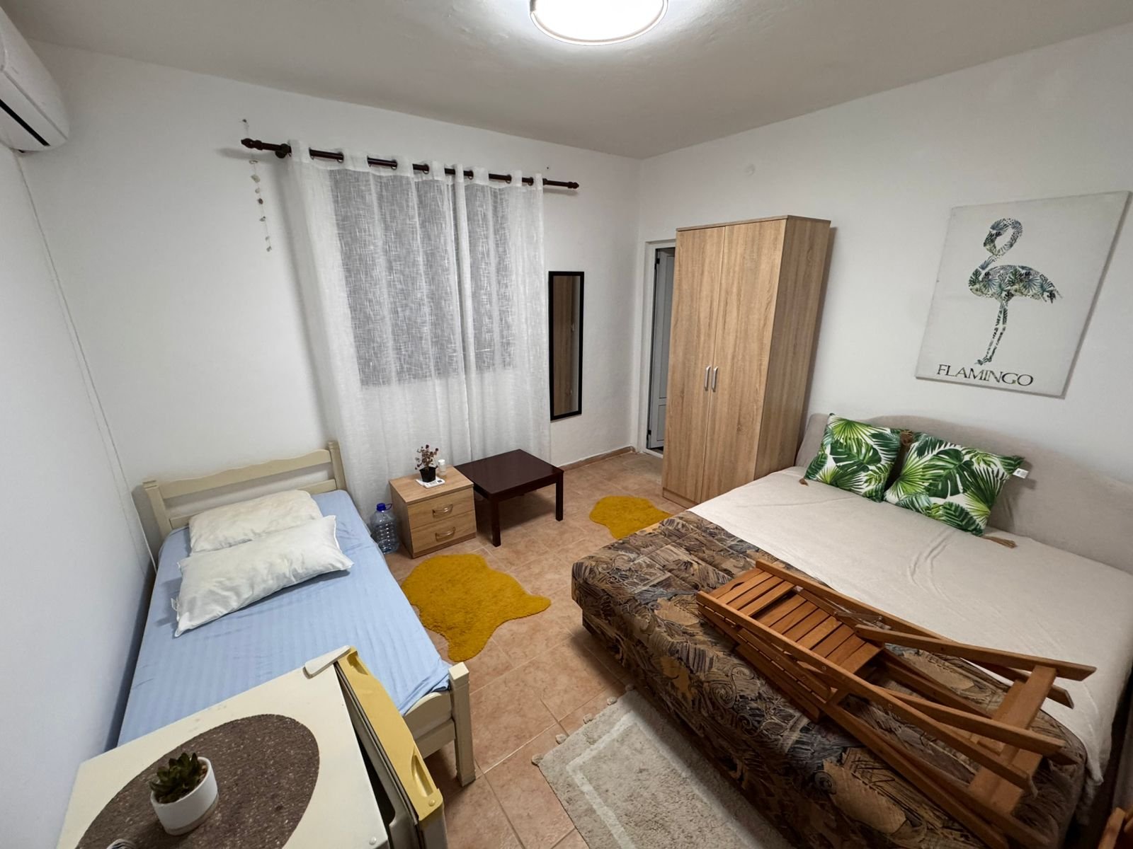 Charming Ulcinj bedroom: single & double beds, modern wardrobe, cozy rugs, stylish decor. Ideal investment on immorenta.me.