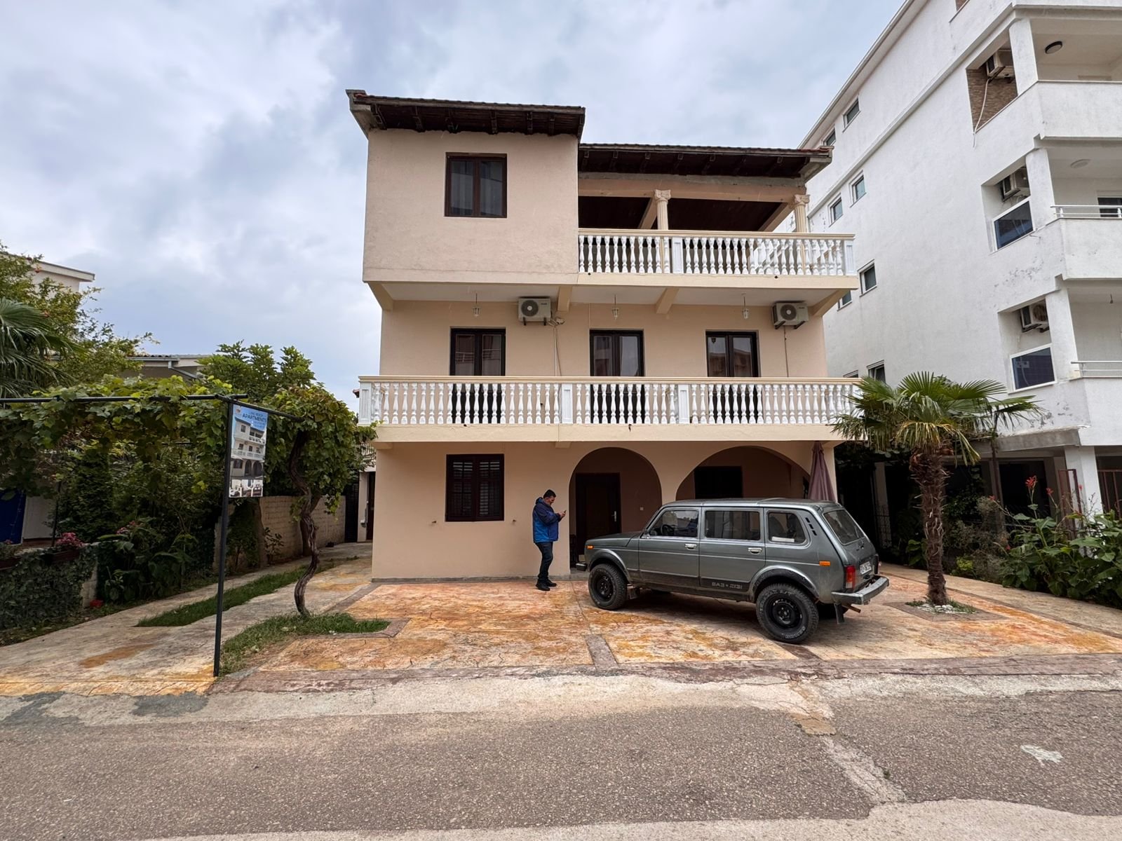 Modern three-story beige residence with balconies, tiled roof, and palm&mdash;prime Ulcinj investment via immorenta.me by ekosphere doo.