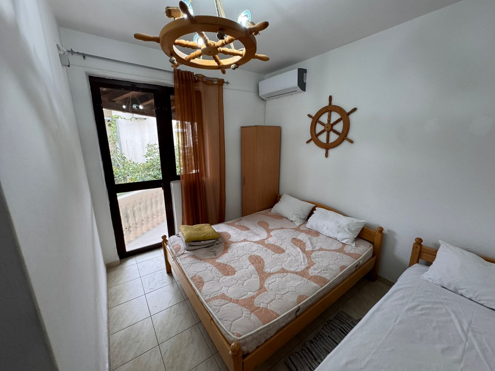 Charming Ulcinj bedroom with double and single beds, nautical details, and private glass door&mdash;ideal Montenegro real estate investment.
