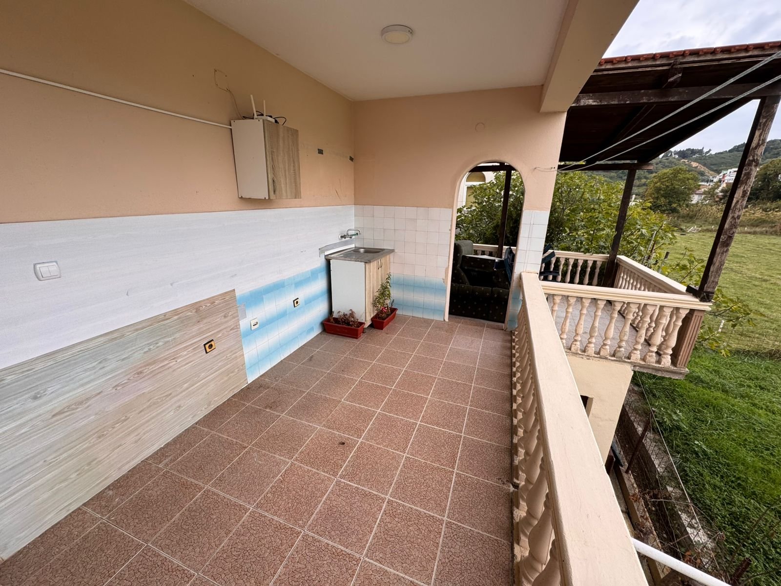 Spacious tiled balcony in Ulcinj with sink, covered seating, and peaceful green views&mdash;ideal Montenegro investment at immorenta.me.