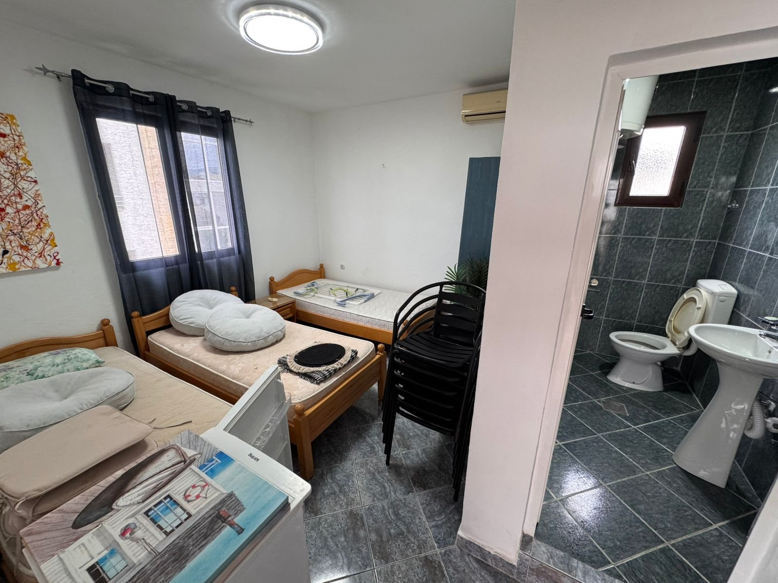 Cozy Ulcinj investment: compact room with twin beds, window, A/C, ensuite green-tiled bath. See more on immorenta.me by ekosphere doo!.