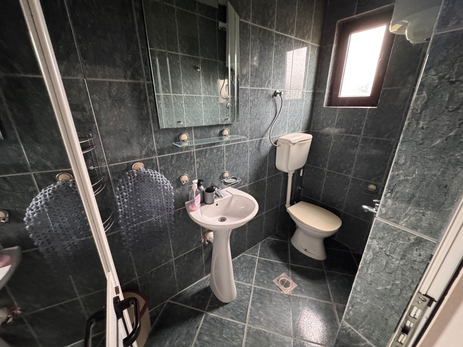 Stylish bathroom with elegant dark green tiles, modern fixtures, natural light&mdash;prime Ulcinj investment via immorenta.me by ekosphere doo.