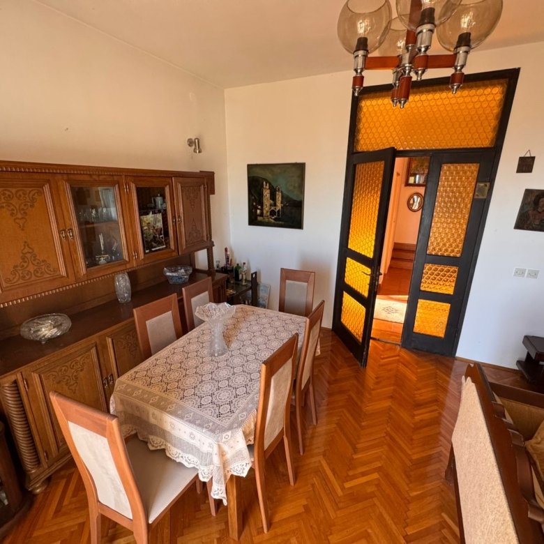 Spacious Ulcinj dining room: wooden table, elegant lace, 6 chairs, glass doors, ambient d&eacute;cor. Invest with immorenta.me.