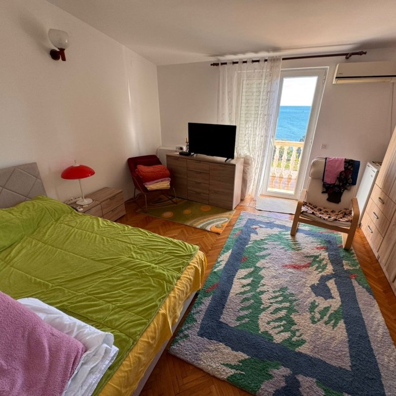 Modern Ulcinj bedroom with sea view, glass balcony doors, vibrant rug, and stylish furnishings. Listed on immorenta.me by ekosphere doo.