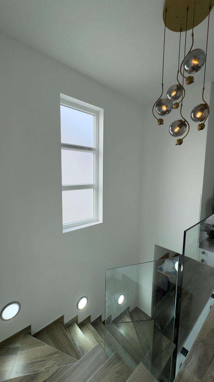 Elegant staircase with wood-patterned steps, glass railing, and modern lighting&mdash;ideal Ulcinj investment at immorenta.me by ekosphere doo.