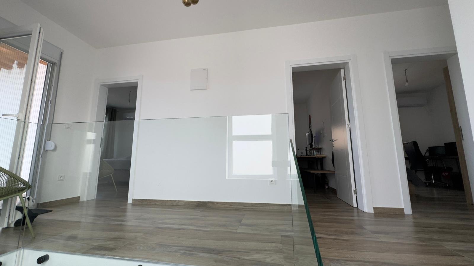 Contemporary Ulcinj apartment: sleek wood floors, white walls, open plan, glass feature. Prime investment via immorenta.me.