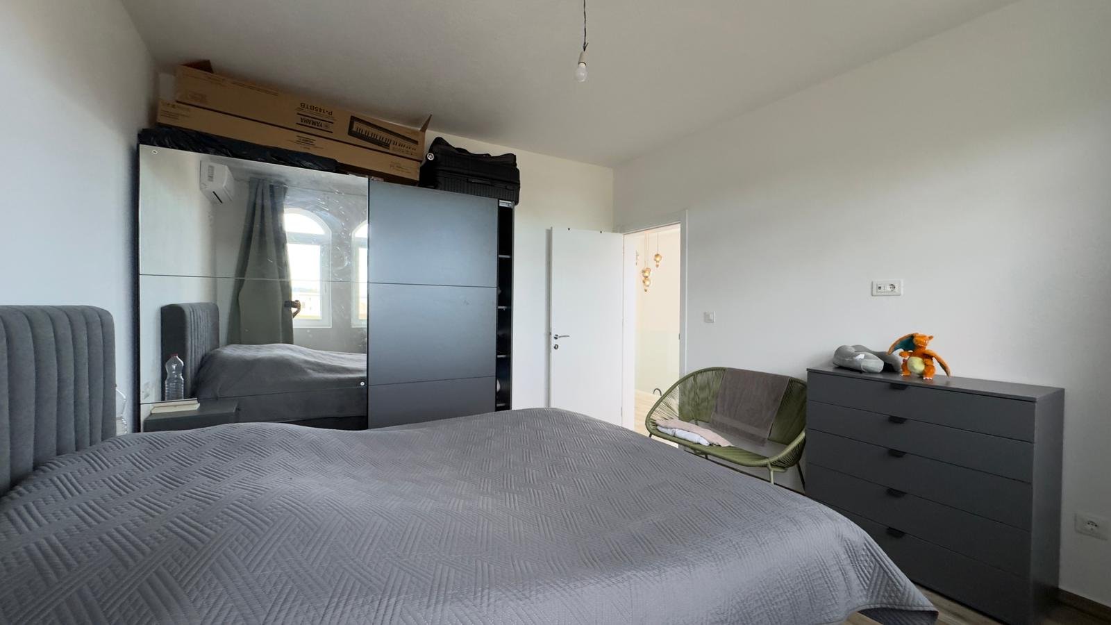 Modern Ulcinj bedroom with stylish gray bed, mirrored wardrobe, and ample storage&mdash;exclusive on immorenta.me by ekosphere doo.